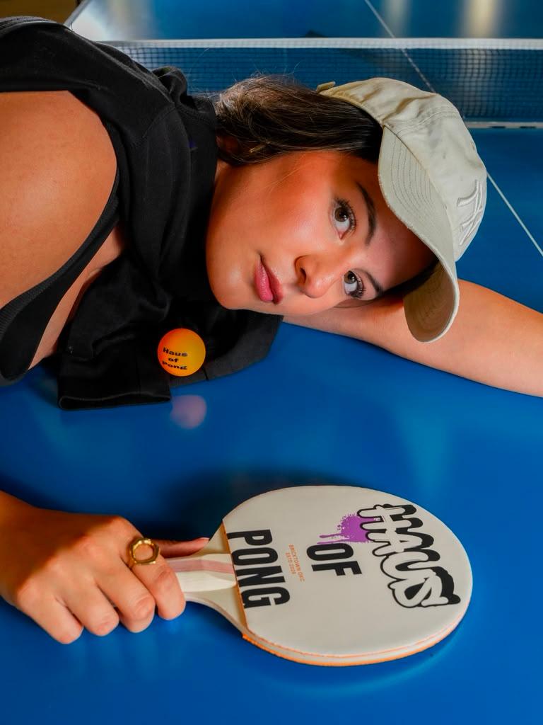 A player resting by the net, paddle in hand, at Haus of Pong